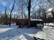 Backyard covered in snow features a small structure with a snow-covered roof, and bare trees against a partly cloudy sky at 8803 S Sleepy Hollow Rd, Waldron, IN 46182
