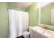 Bright bathroom with green walls featuring a shower with white curtain, a toilet, and a white vanity sink at 10266 Hatherley Way, Fishers, IN 46037