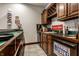 Wet bar featuring wood cabinets, tile backsplash, and a stainless steel under-counter refrigerator at 10554 Hyde Park, Carmel, IN 46032