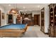 Basement entertainment area with a pool table and custom bar with wood cabinets at 10554 Hyde Park, Carmel, IN 46032