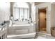 Bright bathroom featuring a luxurious soaking tub beneath a large arched window and glass-doored shower at 10554 Hyde Park, Carmel, IN 46032