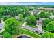 An aerial view shows surrounding neighborhood, landscaping, mature trees, and lush greenery at 10906 Camden Ct, Fishers, IN 46038