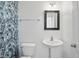 Charming powder room featuring blue leaf wallpaper, a pedestal sink, and a framed mirror for an elegant and modern aesthetic at 1111 Cavendish Dr, Carmel, IN 46032
