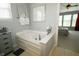 Well-lit bathroom showcasing a tub, white cabinets, and tile flooring at 11727 Wedgeport Ln, Fishers, IN 46037