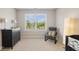Bright bedroom with a large window, dresser, chair, and modern floor lamp with a crib partially pictured at 13868 Broad Mdw, Carmel, IN 46032