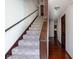 Carpeted staircase with dark wooden railing in a home's entryway, adjacent to hardwood flooring and neutral walls at 16226 Montrose Ln, Westfield, IN 46074
