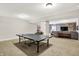 Open basement area with ping pong table, leading to a cozy lounge area with wood accent wall and comfortable seating at 16890 Catkins Ct, Westfield, IN 46074