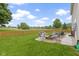 Spacious backyard with lawn, a wood fence, trees, and a stone patio with seating surrounding a firepit at 18711 Crestline Ct, Noblesville, IN 46060