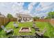 Landscaped backyard with a stone fire pit area surrounded by chairs and a patio with an umbrella-covered table at 18760 Pilot Mills Dr, Noblesville, IN 46062