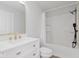 White bathroom features a vanity with marble countertop, gold fixtures, and a tiled shower with white subway tile at 2302 S Pennsylvania St, Indianapolis, IN 46225