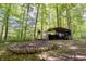 Wooded backyard features a fire pit and an open shed for storage, surrounded by lush trees at 3273 Bailey Dr, Morgantown, IN 46160