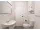 Small bright bathroom features a pedestal sink and a toilet with tiled floors at 370 N Bazil Ave, Indianapolis, IN 46219