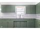 Close up of a kitchen showcasing the green cabinets, subway tile, sink, and countertops at 370 N Bazil Ave, Indianapolis, IN 46219