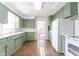 Well-lit kitchen with green cabinets, subway tile backsplash, and stainless steel sink at 370 N Bazil Ave, Indianapolis, IN 46219
