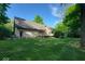 Rear exterior view of a home with a spacious yard, deck, and mature trees at 3917 Knoll Wood Ln, Anderson, IN 46011