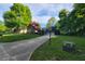 View of a long driveway leading to a lovely home surrounded by mature trees and a well-manicured lawn at 3917 Knoll Wood Ln, Anderson, IN 46011