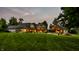 Beautiful backyard at dusk showcasing the sprawling lawn, illuminated house, and outdoor living spaces at 4242 Watson Rd, Greenwood, IN 46143
