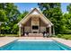 Outdoor living at its finest, a stunning pool house with outdoor kitchen and fireplace overlooks a sparkling pool at 4242 Watson Rd, Greenwood, IN 46143