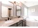 Modern bathroom featuring double sinks, granite countertops, and a soaking tub by the window at 450 Columbia Ct, Greenwood, IN 46142