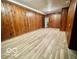 A basement with wood paneling, vinyl flooring, and access to another room at 5222 Nob Ln, Indianapolis, IN 46226
