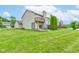 Back exterior view of the home, with a patio, green lawn, and lake views at 5372 Bay Harbor Dr, Indianapolis, IN 46254