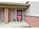 View of front porch showcasing the red storm door, brick columns, and pot of colorful flowers at 5372 Bay Harbor Dr, Indianapolis, IN 46254