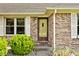 Close-up of the brick home's front door and window with white shutters and green bushes at 551 Windward Ln, Plainfield, IN 46168