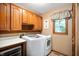 Functional laundry room with modern washer, dryer, wooden cabinets and window at 6575 Robin Hood Dr, Indianapolis, IN 46227