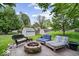 Spacious backyard featuring outdoor furniture, a stone fire pit, and storage sheds surrounded by lush greenery at 7345 Monon Cir, Indianapolis, IN 46256