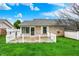 Backyard view of a brick house with a white picket fence, utility shed, and lush green lawn on a sunny day at 7840 Park Ward Pl, Indianapolis, IN 46259