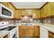 Corner of kitchen featuring wooden cabinets, tile backsplash, and white appliances at 7840 Park Ward Pl, Indianapolis, IN 46259