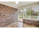 Bright sunroom featuring brick accent wall, tile floors, ceiling fan and view of backyard through a window and open door at 7840 Park Ward Pl, Indianapolis, IN 46259