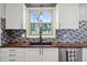 Bright kitchen featuring butcher block countertops, stylish backsplash, stainless steel dishwasher, and modern fixtures at 7910 Teel Way, Indianapolis, IN 46256