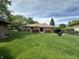 Expansive backyard featuring a well-kept lawn, brick house, deck, and mature trees, perfect for outdoor living at 9521 Gemini Dr, Indianapolis, IN 46229