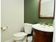 Cozy bathroom with dark green accent wall, a wooden vanity, and white fixtures at 10764 Northhampton Dr, Fishers, IN 46038