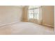 Empty bedroom with carpet flooring, large window, and neutral color palette at 11438 Winding Wood Dr, Indianapolis, IN 46235