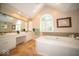 Bathroom featuring double sinks, large tub, and a sunny window at 11536 Woods Bay Ln, Indianapolis, IN 46236