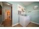 This laundry room features washer, dryer, wood look floors and teal painted walls at 11536 Woods Bay Ln, Indianapolis, IN 46236