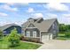 View of the side of the house with a two-car garage and well-manicured lawn near the pond at 12052 Northface Dr, Noblesville, IN 46060