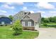 View of the side of the house with a two-car garage and well-manicured lawn near the pond at 12052 Northface Dr, Noblesville, IN 46060