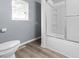 Bathroom area features a shower and toilet near a window with blinds, for natural light at 1225 S Monroe St, Muncie, IN 47302