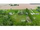 Expansive aerial view of multi-home properties, showcasing lush greenery, a tennis court, and agricultural fields at 12945 E 100 N, Columbus, IN 47203