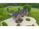 Aerial view of a stately brick home with a circular driveway, three-car garage, and well-manicured grounds at 12945 E 100 N, Columbus, IN 47203