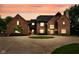 Stunning brick home at twilight featuring a circular driveway and beautiful landscaping at 12945 E 100 N, Columbus, IN 47203