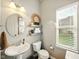 Cozy powder room with a pedestal sink, decorative mirror, and a window providing natural light at 165 N Bend Dr, Greenwood, IN 46142