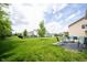A grassy backyard with a black fence features patio seating, mature trees and a beautiful green space at 17696 Arryne E Dr, Noblesville, IN 46062