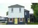 Shot of the home's front showing white siding, black accents, shutters, and a cheerful yellow front door at 1802 Woodlawn Ave, Indianapolis, IN 46203