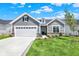 Charming home with a two-car garage, gray siding, stone accents, and a well-manicured lawn on a beautiful day at 19725 Highclere Lane, Sheridan, IN 46069