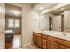 Bright bathroom with double sinks, wood cabinets and a glimpse into an adjacent bedroom at 2055 Mulsanne Dr, Zionsville, IN 46077