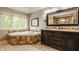 Bright bathroom features a jacuzzi, a dark wood vanity, and a large window at 2055 Mulsanne Dr, Zionsville, IN 46077